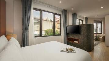 A hotel room with a large bed, a TV mounted on a marble wall, and a view of the outside.