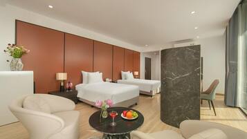A modern hotel room with two beds, a sitting area with a table, and a large window.