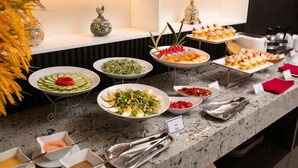Un bufé con diversos platos, incluyendo ensaladas, frutas y postres.