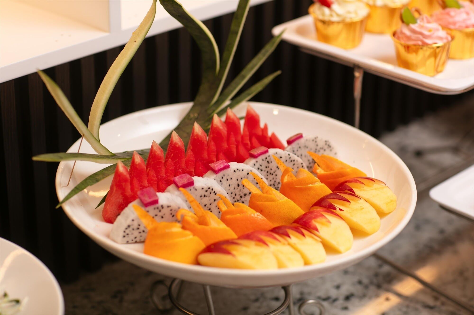 Una bandeja de frutas con pitahaya, mango y sandía sobre un plato blanco.
