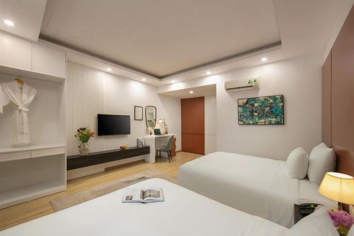 Une chambre d’hôtel moderne équipée d’un lit, d’un bureau, d’une télévision et d’un tableau au mur.