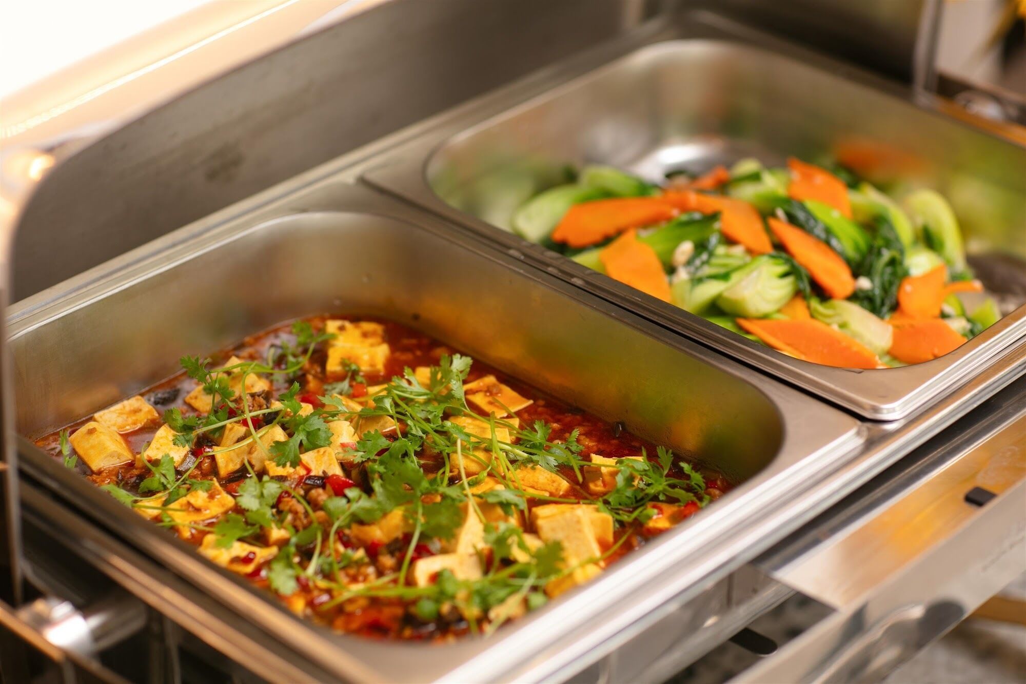 A buffet with two dishes: one with tofu and vegetables, and another with mixed vegetables.