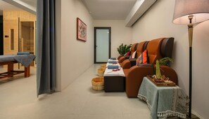 Un cuarto de spa con una camilla de masaje, un sofá con toallas y una mesita con adornos.