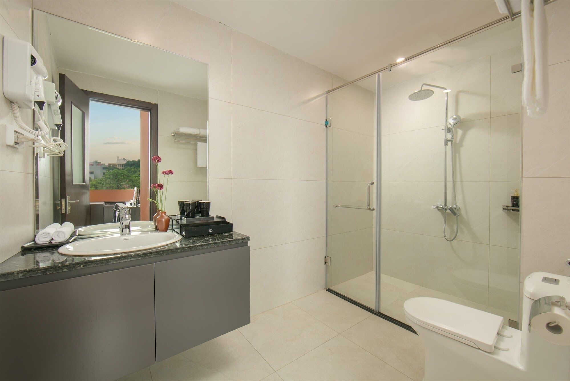 A modern bathroom with a glass-enclosed shower, a white toilet, and a vanity with a sink and mirror.