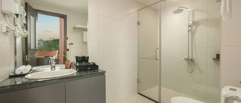 A modern bathroom with a glass-enclosed shower, a white toilet, and a vanity with a sink and mirror.