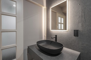 Ein modernes Badezimmer mit einem großen Spiegel, einem Aufsatzwaschbecken und einer strukturierten Wand.