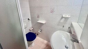 Un baño pequeño con inodoro, lavamanos y zona de ducha.