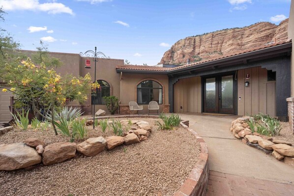 A modern house with a patio, a rock garden, and a view of a mountain.