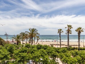 A beach with palm trees, a ship in the distance, and a clear sky.