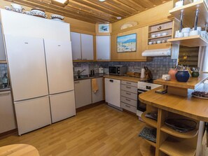 A compact kitchen with a refrigerator, microwave, and stove. There are wooden cabinets and a wooden countertop. - Villa kopararova by Interhome (Inari)