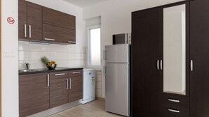 Een moderne keuken met donkerhouten kastjes, een roestvrijstalen koelkast en een compacte vaatwasser.