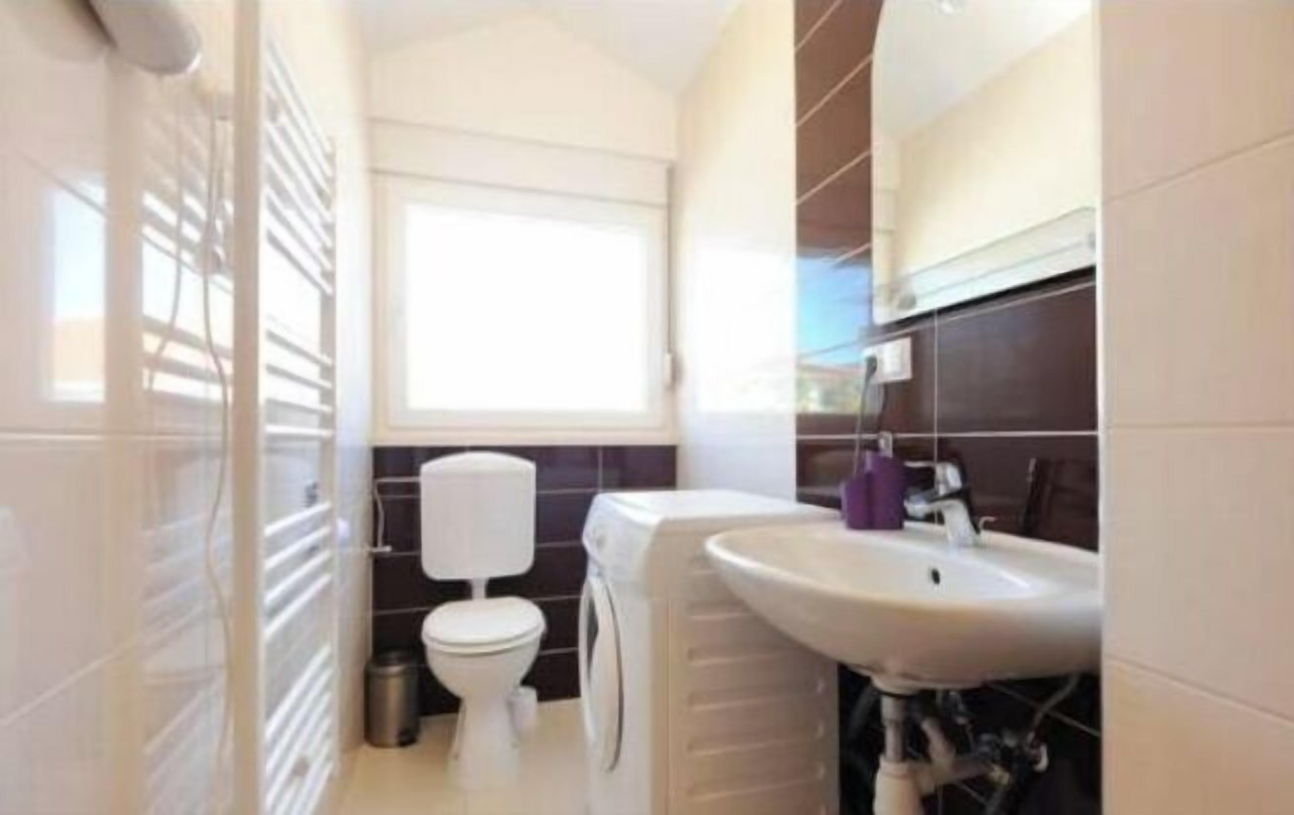 A small bathroom with a toilet, a sink, and a window.
