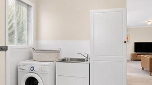 Un espace buanderie comprenant un lave-linge, un sèche-linge et un évier.