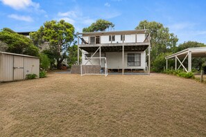 A two-story house with a covered porch and a fenced yard. - Island Treetops by Ready Set Stay (Smiths Beach)