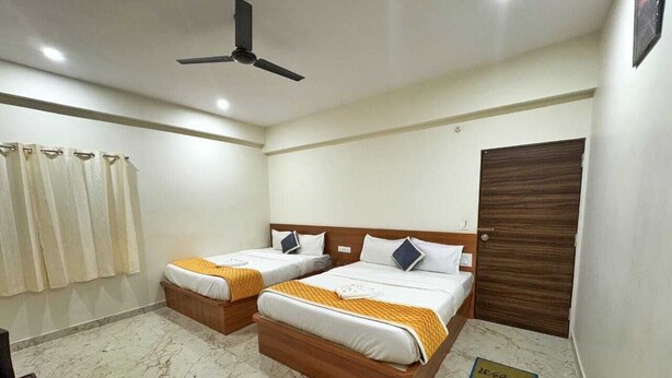 Habitación de hotel con dos camas, ventilador de techo, piso de mármol y felpudo.
