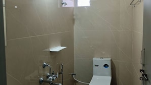 Un baño pequeño con ducha, inodoro y lavamanos.