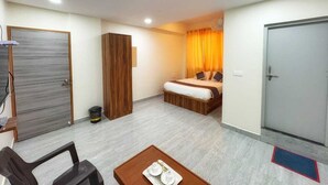 Una habitación de hotel funcional con cama, escritorio, armario y una mesita con bandeja.