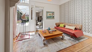 Un salon spacieux avec un canapé rouge, une table basse en bois et un mur orné d’un motif.