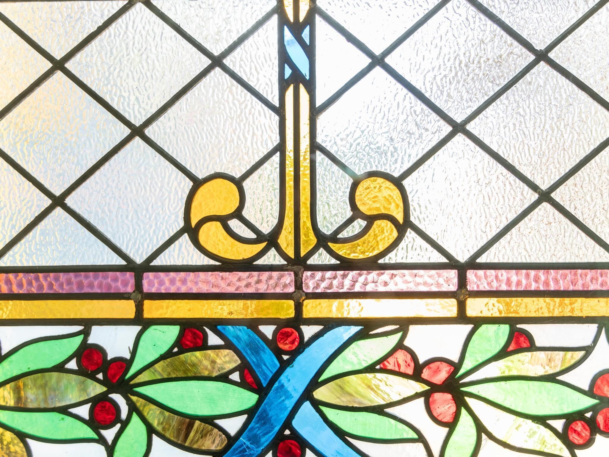 A stained glass window with geometric patterns and floral motifs.