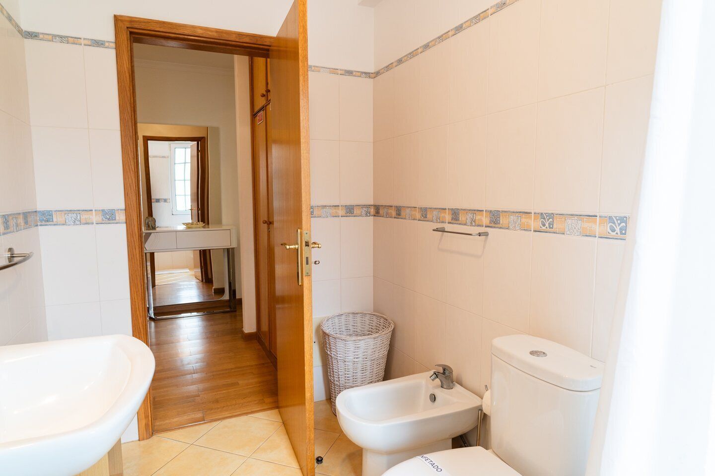 Ein Badezimmer mit Holztür, Waschbecken, Bidet und Toilette.