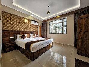 A modern bedroom with a large bed, wooden headboard, and a window with bars. - Alicos Residency (Sulthan Bathery)