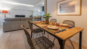 Ein Essbereich mit Holztisch, Korbstühlen und einer Pendelleuchte.