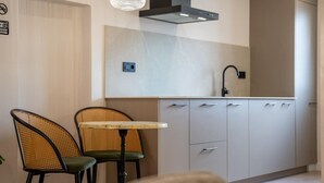 Eine moderne Küche mit Essbereich, ausgestattet mit einem Tisch, zwei Stühlen, einem Einbauherd und einer Pendelleuchte.
