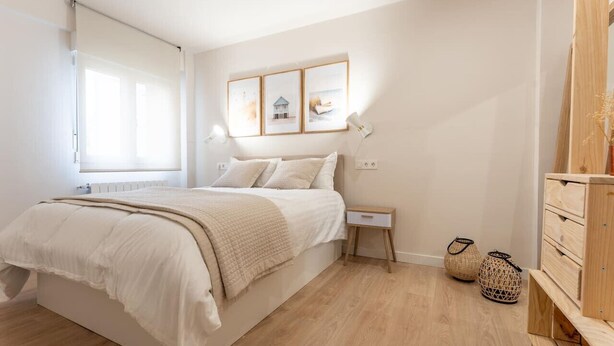 Ein Schlafzimmer mit Bett, Nachttisch, Lampe und einem Wandregal.