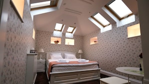A bedroom with a bed, bedside tables, a small table, and skylights. - Les Jardins Carol (Bucharest)