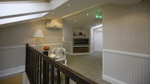 A spacious room with a high ceiling, a fireplace, a television, and a staircase leading to an upper level. - Les Jardins Carol (Bucharest)