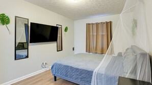 A bedroom with a bed, a TV mounted on the wall, a bedside table, and a window with curtains. - < 1 Mi to Vanderbilt: Nashville Apt (Nashville)