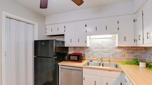 A compact kitchen with white cabinets, a black refrigerator, a microwave, and a dishwasher. - < 1 Mi to Vanderbilt: Nashville Apt (Nashville)