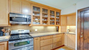 Eine Küche mit Holzausstattung, Edelstahlgeräten und einer Arbeitsplatte aus Granit.