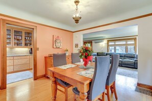 A dining area with a wooden table, chairs, and a vase of flowers. There is a kitchen area with cabinets and a countertop visible in the background. - Charming Tudor-Style Apt Near Green Lake! (Seattle)