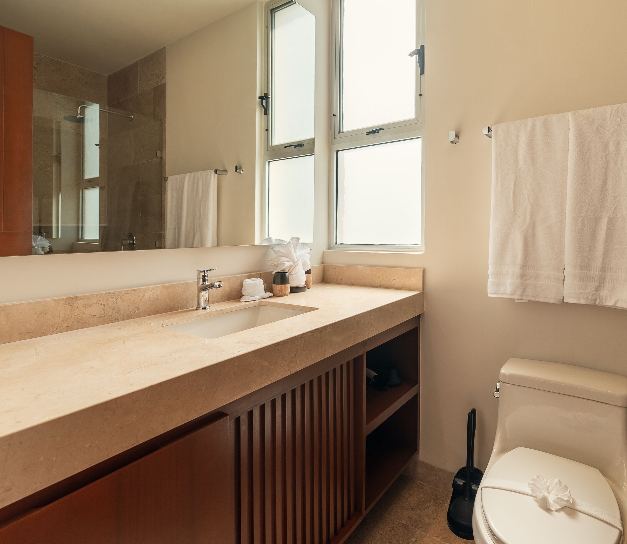 A modern bathroom with a large mirror, a sink, and a toilet.