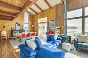 A spacious living area with a large blue sofa, red chairs, and a fireplace. - Decks & Views: Waterfront Shelton Home (Shelton)