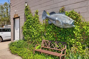 Ein Gebäude mit einer großen Fischskulptur, einer Bank und einem in der Nähe geparkten Auto.