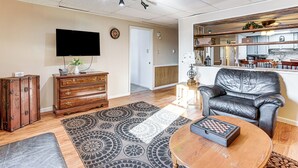 Una sala de estar con televisor de pantalla plana, un sofá de cuero, una mesa de centro de madera y una alfombra estampada.