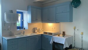 A kitchen with blue cabinets, a sink, a coffee maker, and a stove.