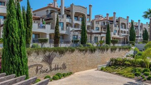 Un hôtel à plusieurs étages, doté de façades en pierre et en stuc, de balcons et d’un jardin aménagé.