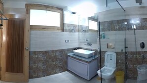 Un baño con puerta de madera, lavamanos, inodoro y zona de ducha.