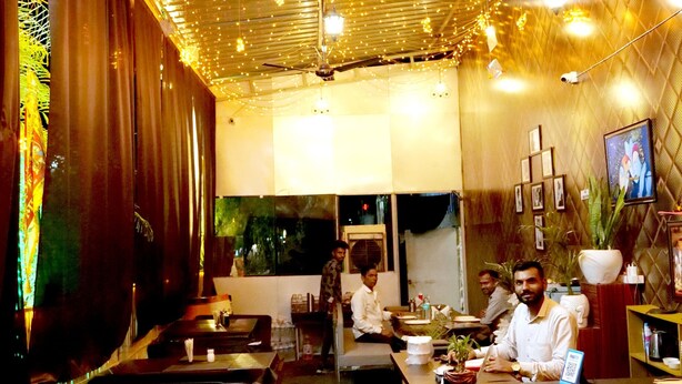 L’intérieur d’un restaurant, avec une boule à facettes, des guirlandes lumineuses et des plantes en pot.