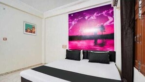 Une chambre à coucher avec un lit, une table de chevet, un téléviseur fixé au mur et un tableau encadré accroché au mur.