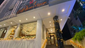A hotel entrance with a staircase, decorated with lights and flowers.