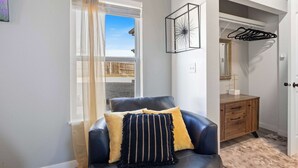 Una habitación con una butaca de cuero, un aparador de madera y una ventana con cortinas de gasa.