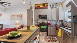 Una cocina moderna con armarios de madera, electrodomésticos de acero inoxidable y un comedor con sofá rojo y mesa de madera.