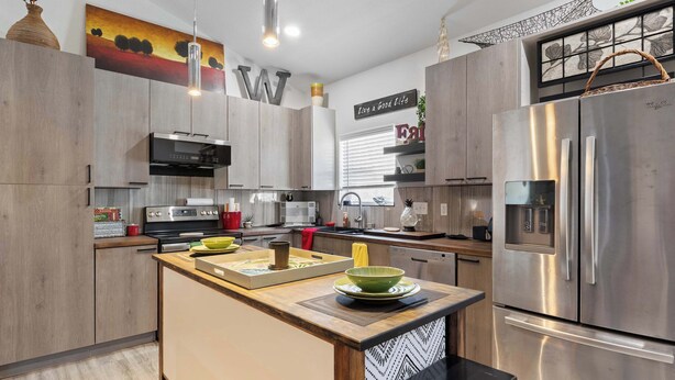 Una cocina moderna con una isla central, electrodomésticos de acero inoxidable y una obra de arte decorativa en la pared.
