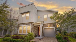 A modern two-story house with a stone facade, a red door, and a garage.