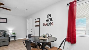 Un coin repas avec une table ronde, quatre chaises et un rideau rouge.