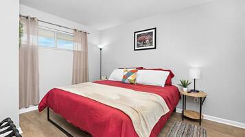 A modern bedroom with a large bed, a bedside table with a lamp, and a framed picture on the wall.